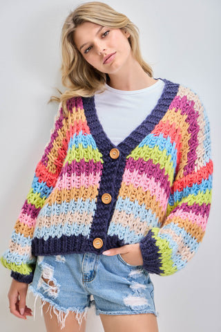 Woman wearing a colorful striped cardigan with a plain background