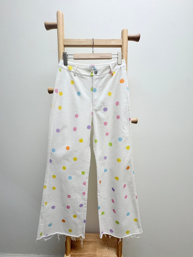 Fabric with colorful polka dots on a wooden loom against a white background