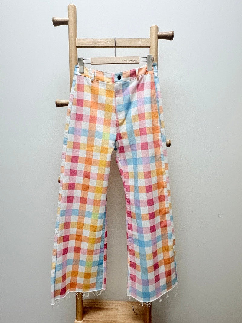Colorful checkered fabric draped over a wooden loom on a plain background