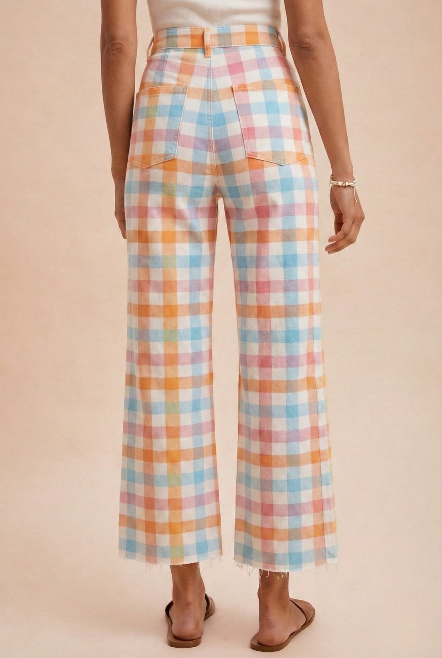 Pastel plaid pants worn by a person on a beige background