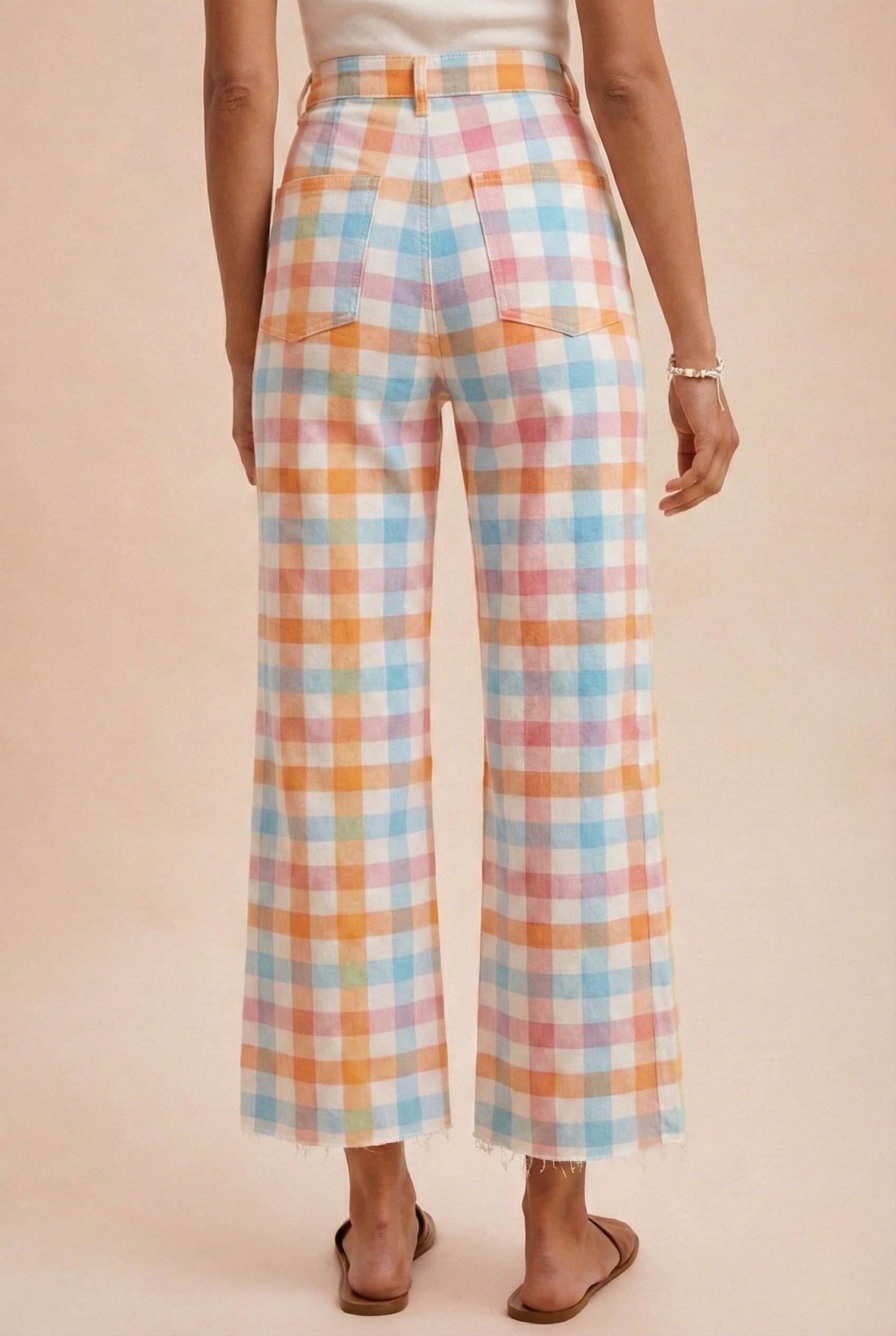 Pastel plaid pants worn by a person on a beige background