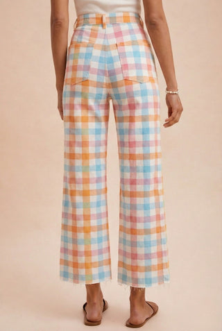 Pastel plaid pants worn by a person on a beige background