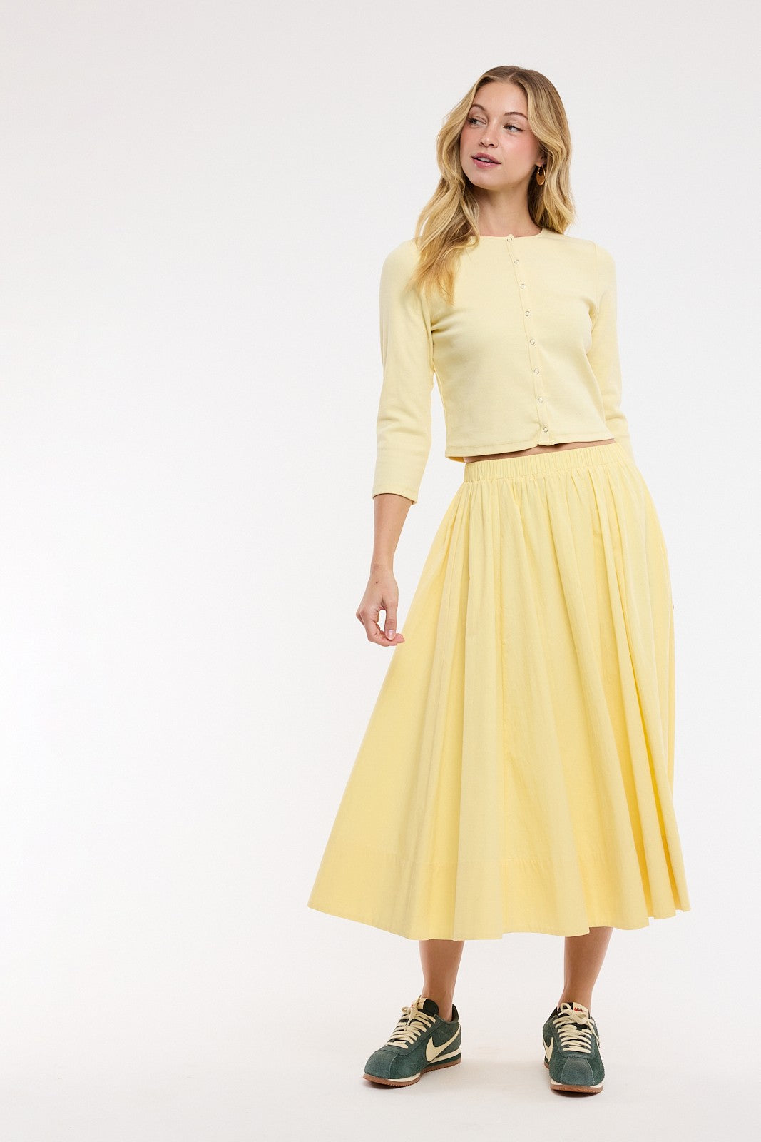 Woman wearing a yellow outfit with a top and skirt on a white background