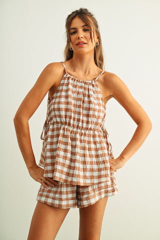 Woman wearing a checkered romper against a plain background