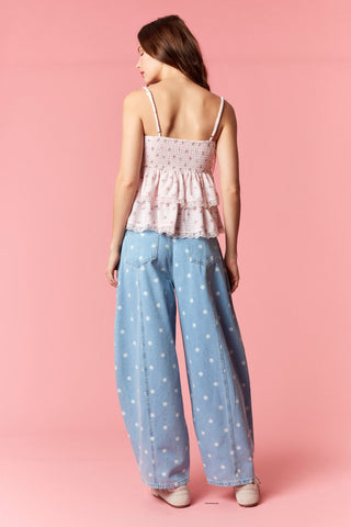 Woman wearing a pink top and blue polka dot pants on a pink background