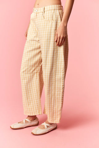 a women wearing yellow checker pants against pink background.