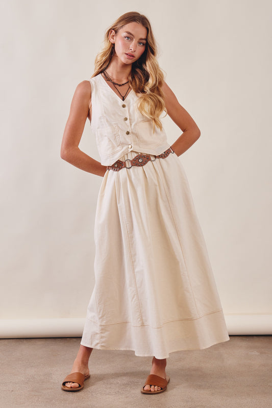 Woman wearing a white dress with a belt against a plain background