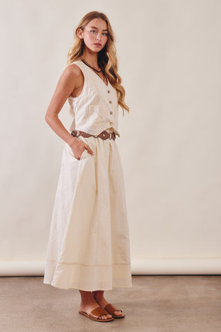 Woman wearing a white dress with buttons standing against a plain background