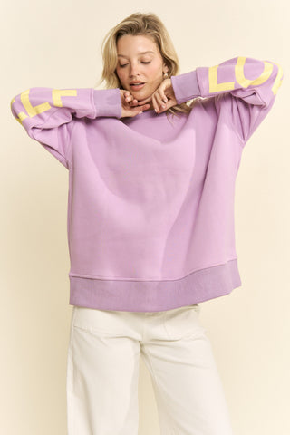 Person wearing a purple sweater with yellow accents on a beige background