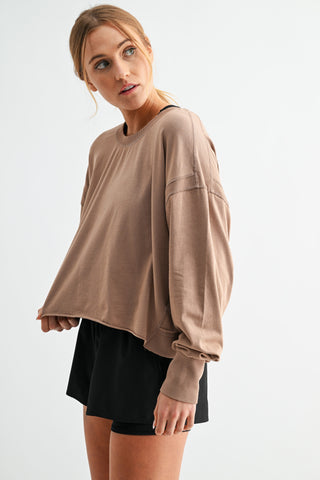 Woman wearing a beige oversized sweatshirt and black shorts on a white background