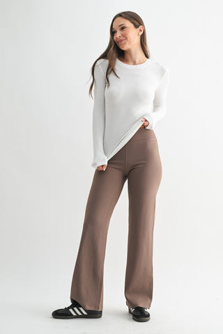 Woman wearing a white top and brown pants on a white background