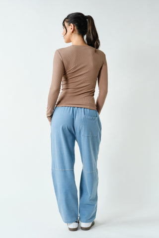 Person wearing a brown top and light blue pants on a white background