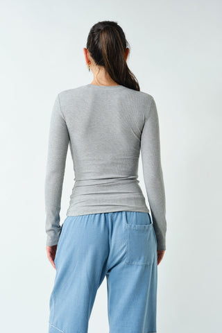 Person wearing a gray long-sleeve top and light blue pants on a white background