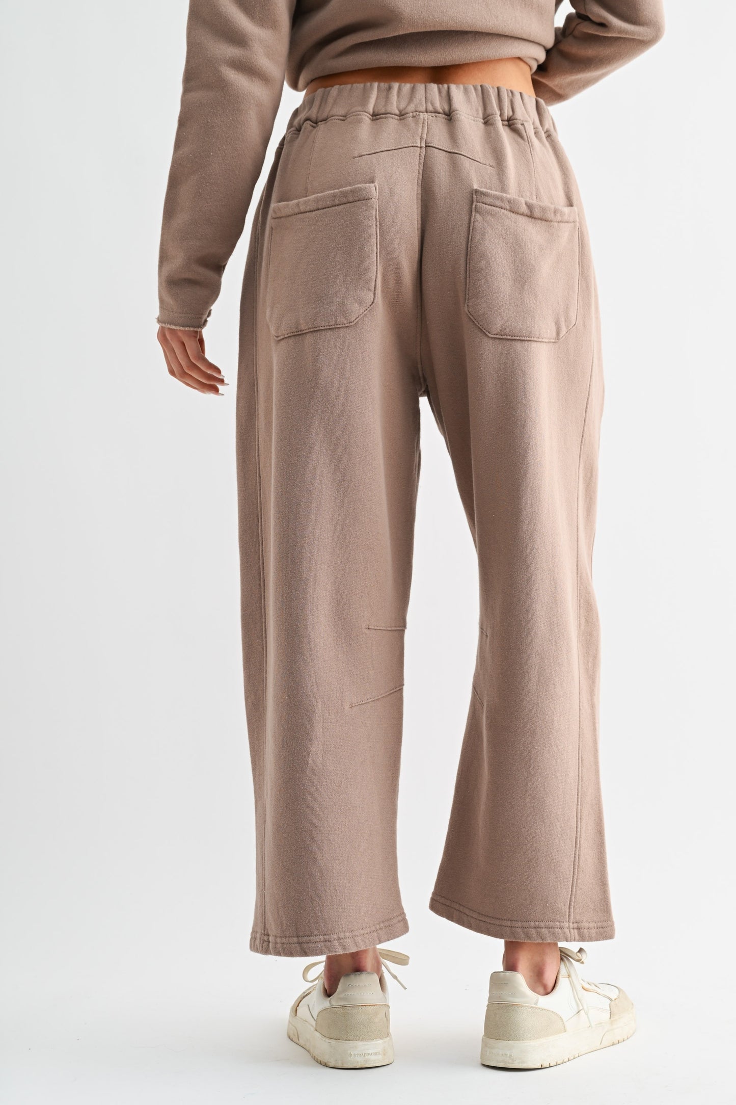 Person wearing beige high-waisted pants on a white background