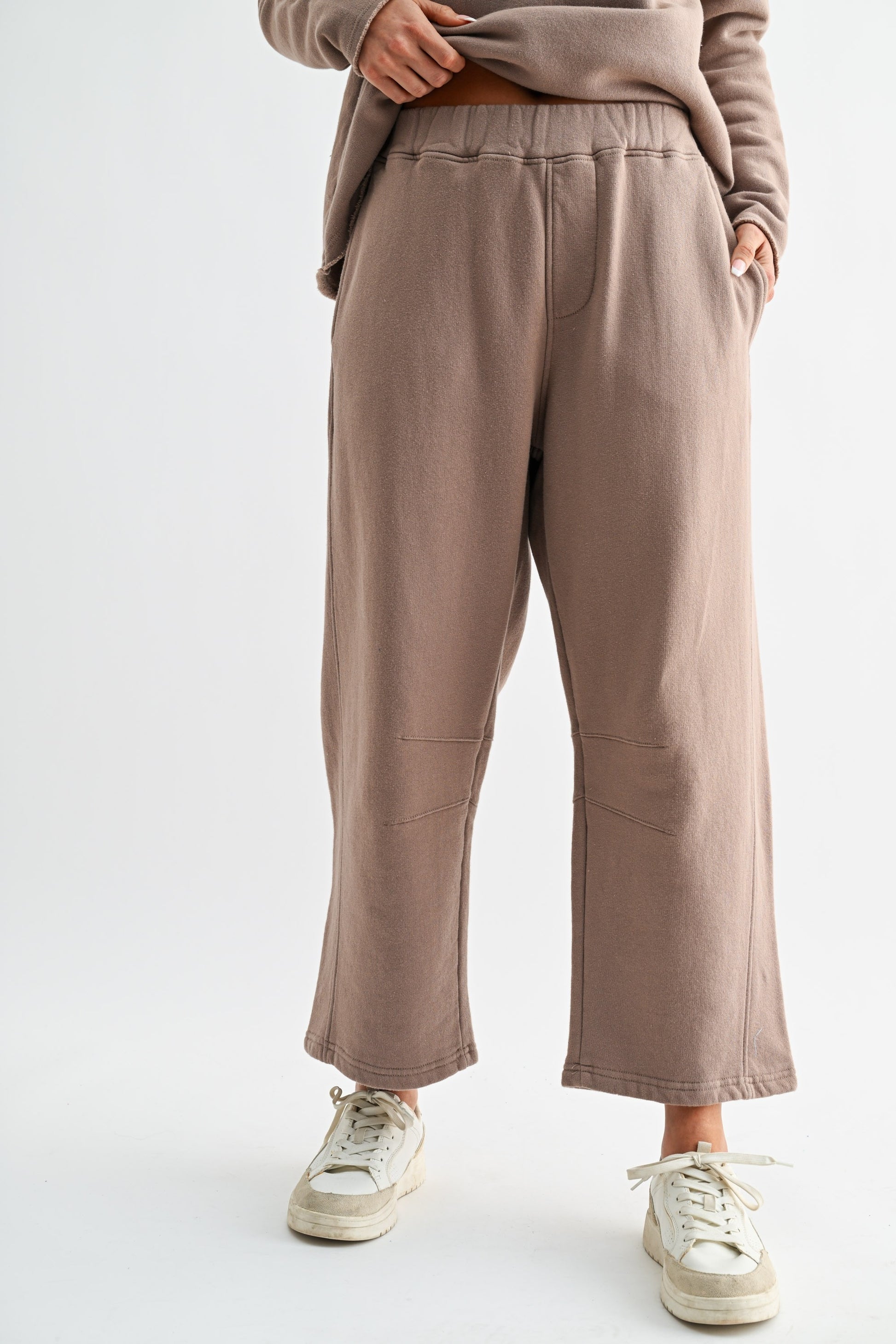 Person wearing brown pants and a matching top on a white background