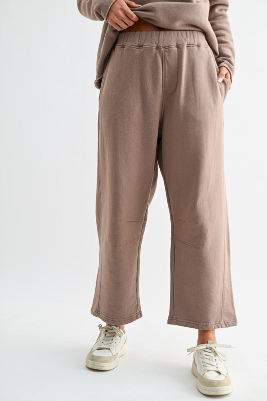 Person wearing brown pants and a matching top on a white background