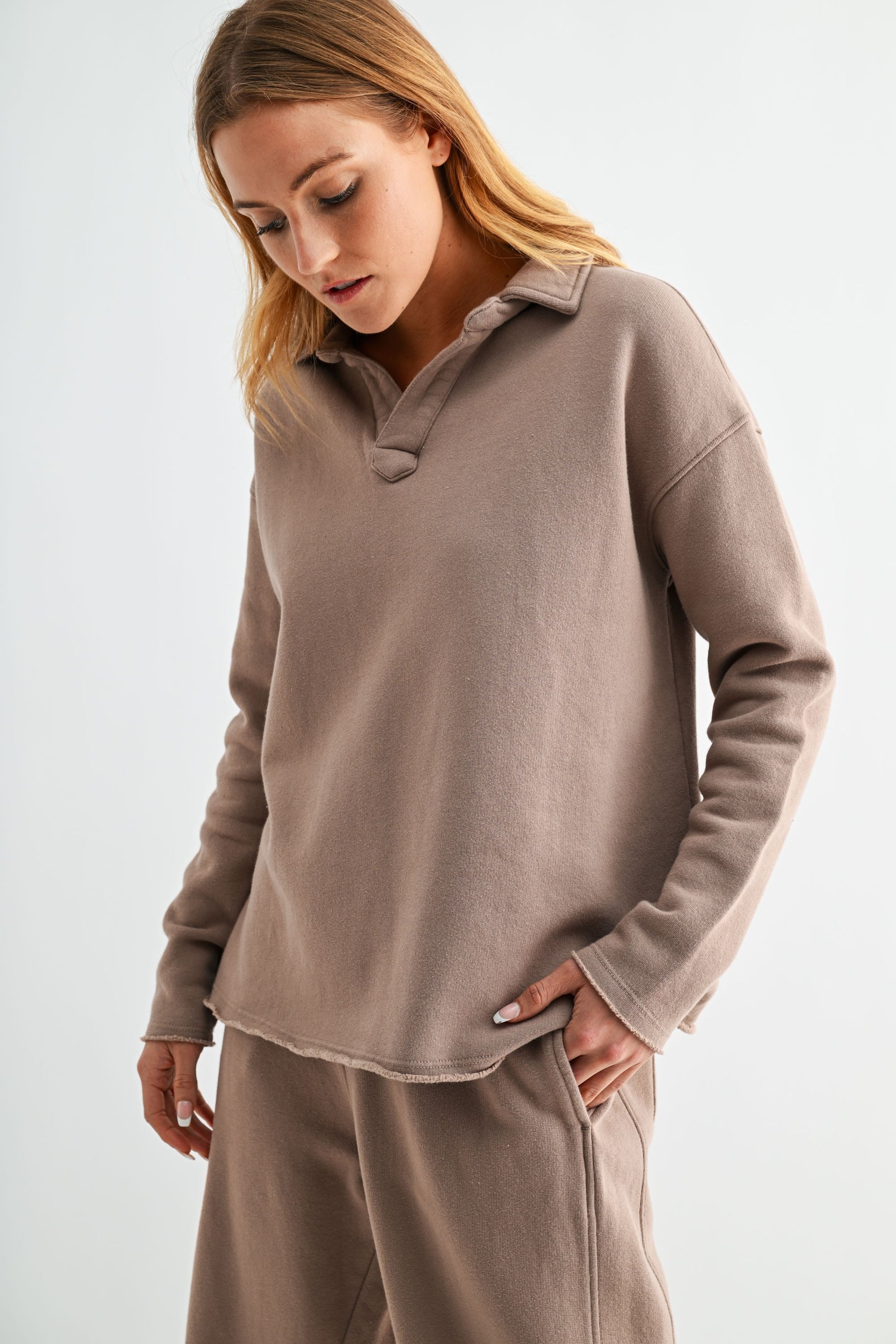 Woman wearing a beige long-sleeve top and pants on a white background