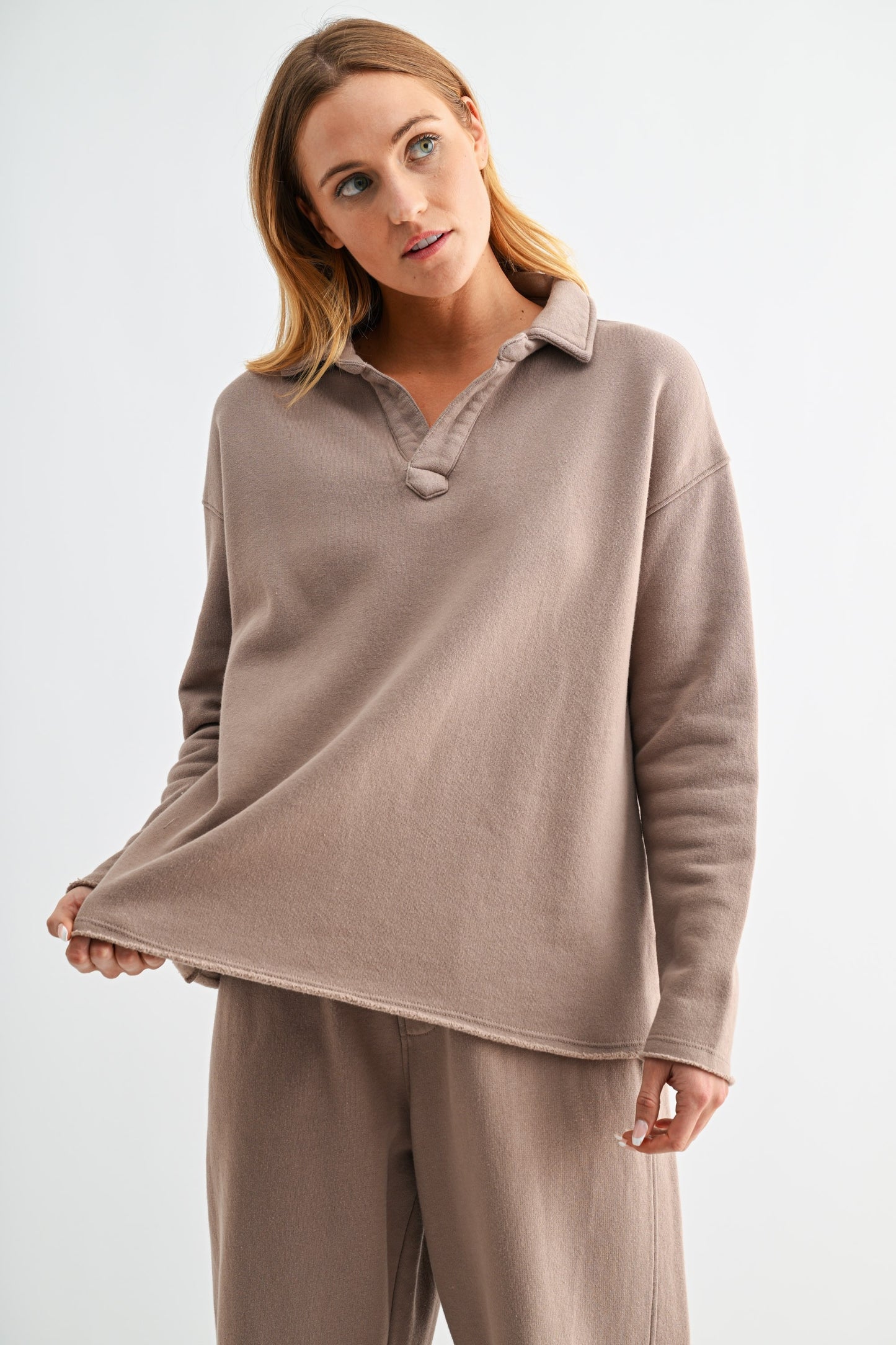 Woman wearing a beige fleece pullover with a collar on a white background