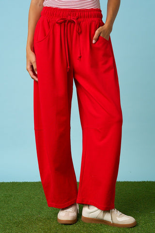 Person wearing red pants and white shoes on a grassy surface with a blue background