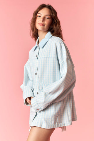 Woman wearing a light blue checkered outfit against a pink background