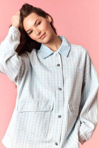Woman wearing a light blue checkered shirt against a pink background