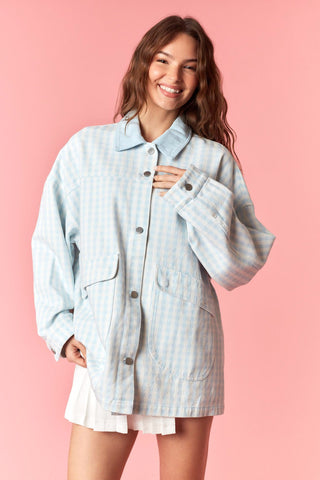 Woman wearing a light blue checkered jacket on a pink background