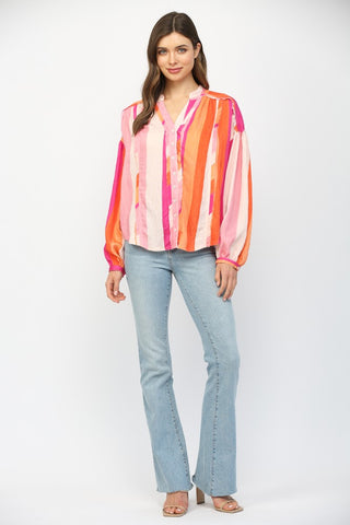 Women wearing a pink and orange stripe button up blouse with blue jeans.