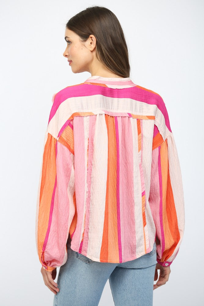 Women wearing a pink and orange stripe button up blouse with blue jeans.