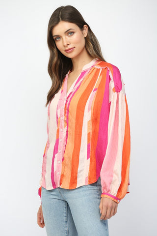 Women wearing a pink and orange stripe button up blouse with blue jeans.