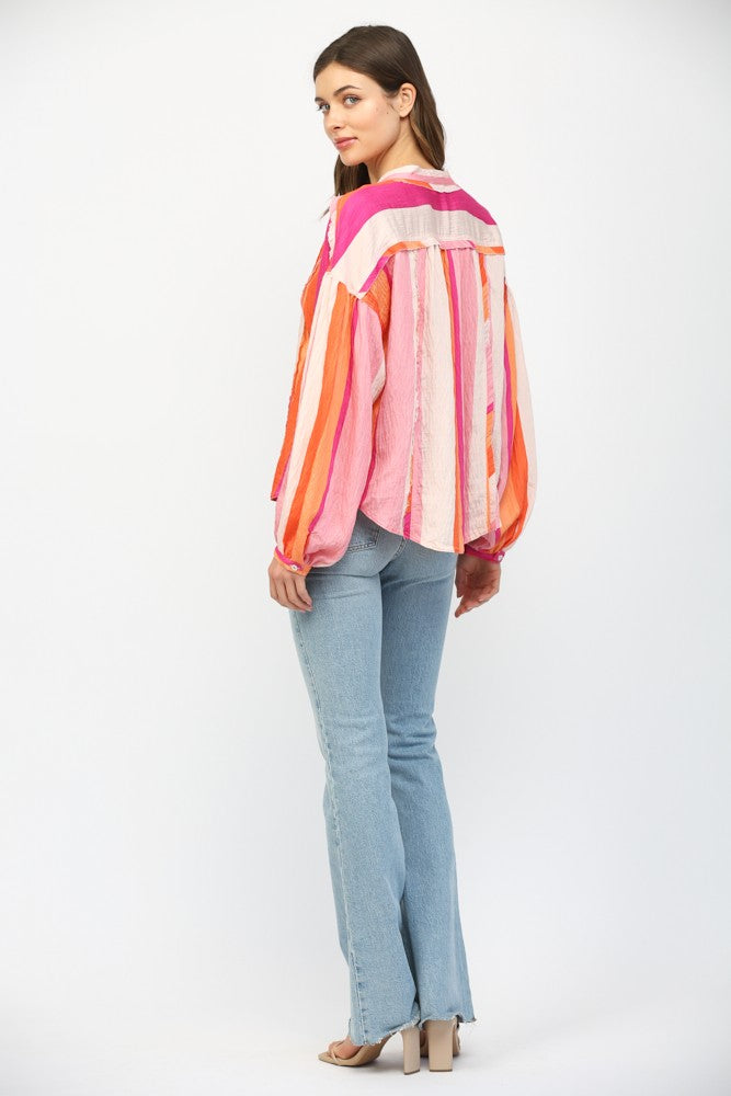 Women wearing a pink and orange stripe button up blouse with blue jeans.