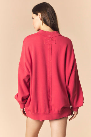 Person wearing a red sweatshirt on a beige background