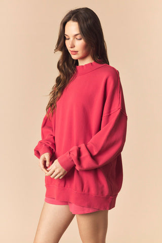 Woman wearing a red oversized sweatshirt against a beige background