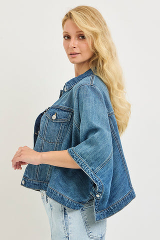 Woman wearing a blue denim jacket on a plain background