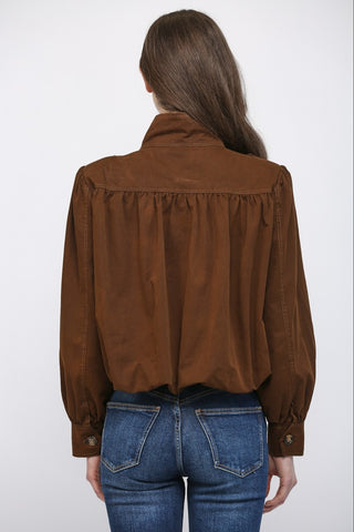 Women wearing a brown button up jacket against a neutral background.