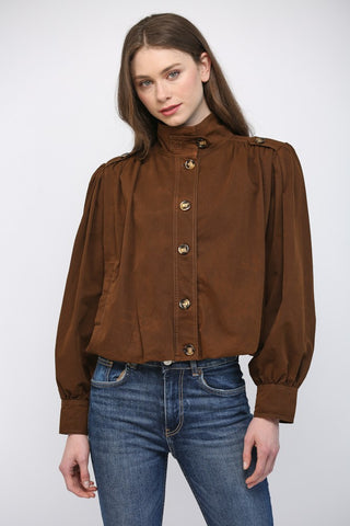 Women wearing a brown button up jacket against a neutral background.