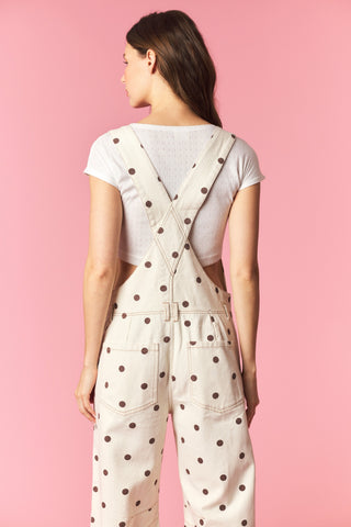 Woman wearing polka dot overalls on a pink background