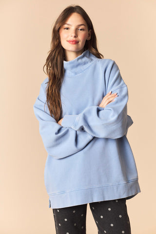 Woman wearing a light blue oversized sweater against a beige background