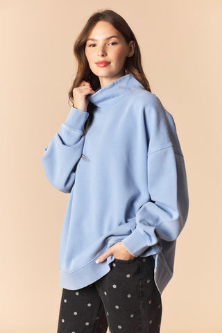 Woman wearing a light blue oversized sweater against a beige background