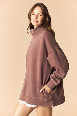 Woman wearing a brown sweatshirt against a beige background