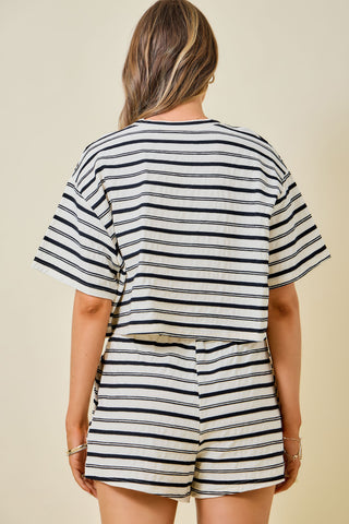 A woman shown from the back wearing a matching striped short-sleeve crop top and shorts set in black, white, and beige.