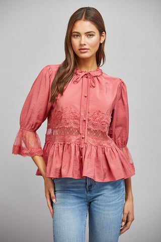 Women wearing a pink lace blouse against a neutral background.