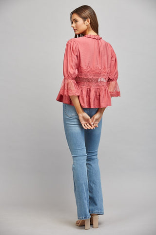Women wearing a pink lace blouse against a neutral background.