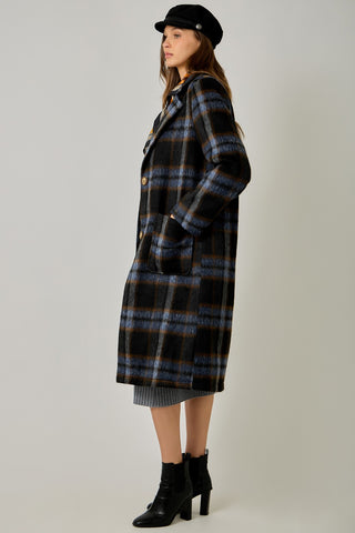 Women modelling a blue plaid coat against a neutral photo background. 
