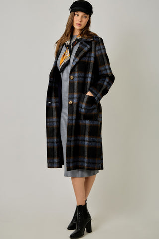 Women modelling a blue plaid coat against a neutral photo background. 
