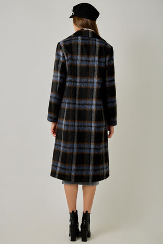 Women modelling a blue plaid coat against a neutral photo background. 