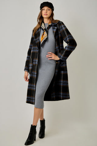 Women modelling a blue plaid coat against a neutral photo background. 