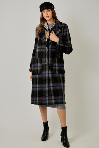 Women modelling a blue plaid coat against a neutral photo background. 