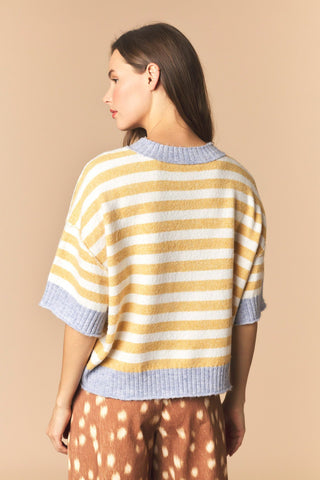 A women wearing a striped cropped sweater against a neutral background. 