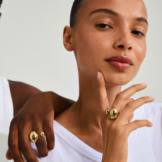 Woman wearing gold rings on a plain background