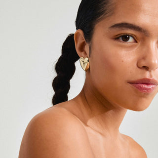 Woman wearing a heart-shaped earring against a plain background